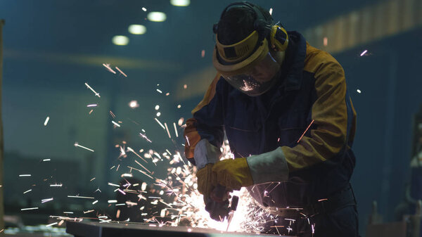 Heavy industry worker at a factory is working with metal on a an