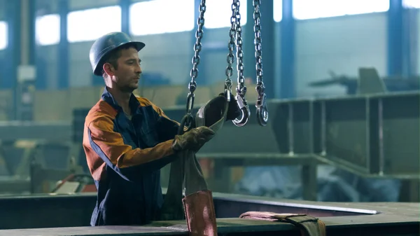 Trabajador de la industria pesada en una fábrica está trabajando con ganchos de un — Foto de Stock