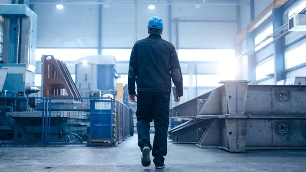 Работник фабрики в каске идет по промышленному заводу — стоковое фото