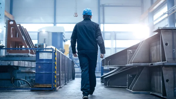 Operaio in un cappello rigido sta camminando attraverso facil industriale — Foto Stock