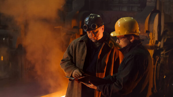 Two Workers Have Conversation and Using Tablet PC in Foundry. Ro