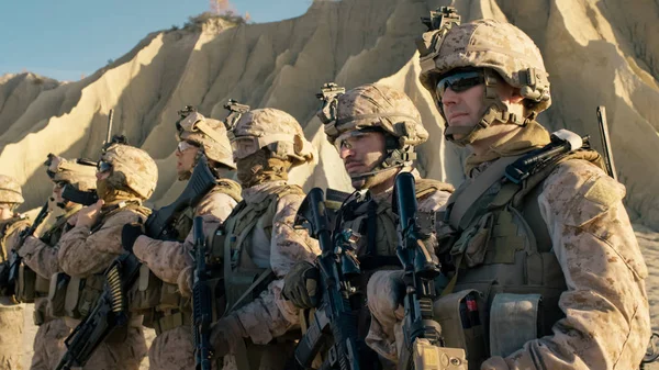 Gruppe voll ausgerüsteter Soldaten steht in einer Schlange in der Wüste — Stockfoto