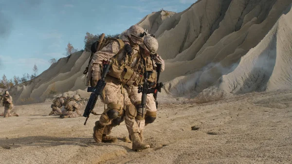 Soldat trägt einen Verletzten bei sich, während andere Mitglieder der Einheit verdeckt — Stockfoto