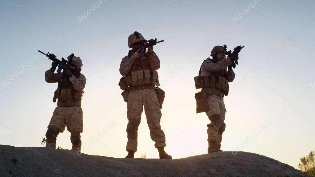 Squad of Three Fully Equipped and Armed Soldiers Standing on Hil