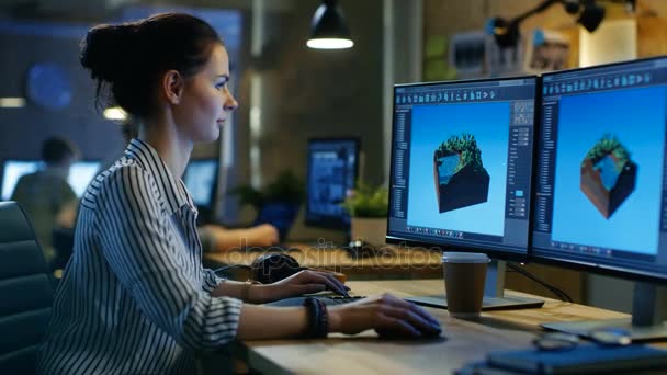 Femme développeuse de jeux travaille sur un level design sur son ordinateur personnel avec deux écrans. Elle travaille dans un espace de bureau créatif . — Video