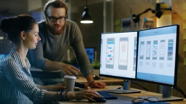 Vrouwelijke Ux Architect heeft bespreking met mannelijke ontwerpingenieur, ze werken op mobiele applicatie laat in de nacht, ze drinkt koffie. In de achtergrond muur met Project kleverige nota's en andere medewerkers van de Studio. — Stockvideo