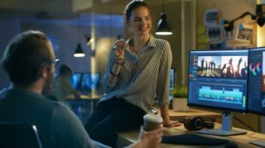 Güzel kadın ve yakışıklı erkek Video editörleri onlar üzerinde çalışıyoruz görüntüleri tartışmak. Onlar birlikte yaratıcı bir stüdyoda çalışmak hoşuna gidiyor.