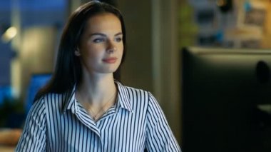 Güzel genç kadın kişisel bilgisayar üzerinde çalışır, o tatlı kameraya gülümsüyor. O bir Modern ofis Loft Studio alanında çalışıyor.