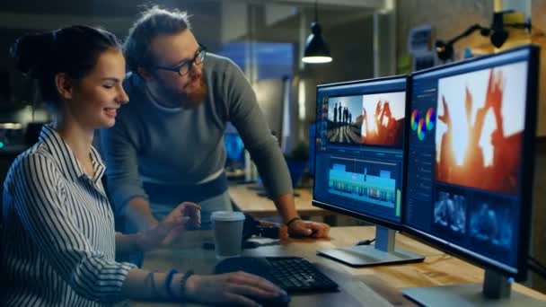 Female Video and Sound Editor Works With Her Male Colleague on a Project on Her Personal Computer with Two Displays. Eles trabalham em um escritório Creative Loft . — Vídeo de Stock