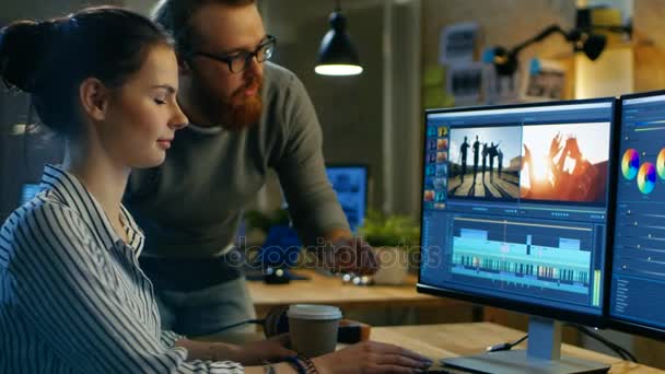 Vrouwelijke Video en geluid Editor werkt met haar mannelijke collega op een Project op haar Personal Computer met twee beeldschermen. Ze werken in een creatieve Loft kantoor. — Stockvideo