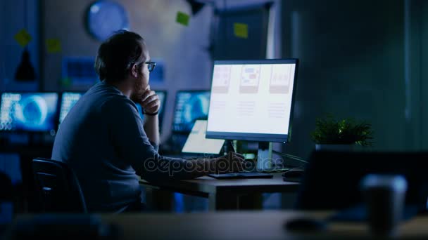 Male Mobile Application Developer trabaja con gráficos en su computadora personal con dos monitores. Trabaja hasta tarde en la noche, en una oficina vacía . — Vídeos de Stock
