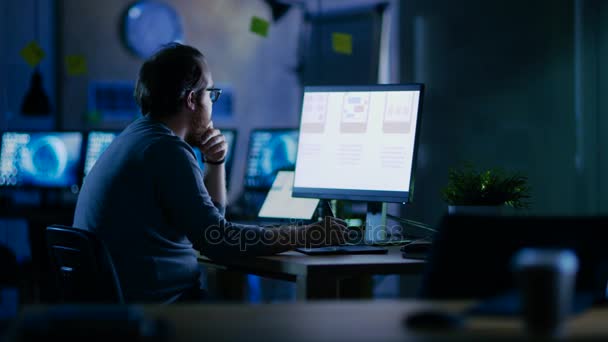 Manliga mobila Application Developer arbetar med grafik på sin persondator med två bildskärmar. Han jobbar sent på kvällen, i ett tomt Office. — Stockvideo