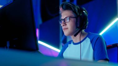 Genç çocuk oyun oynar, rekabetçi Video oyunundan bir esports turnuva / Internet Cafe. Gözlük ve mikrofon kulaklık takıyor.
