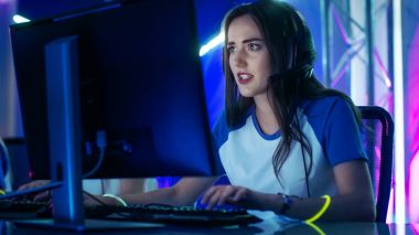 Beautiful Professional Gamer Girl and Her Team Participate in eSport Cyber Games Tournament. She Has Her Headphones and Colorful Band on. clipart