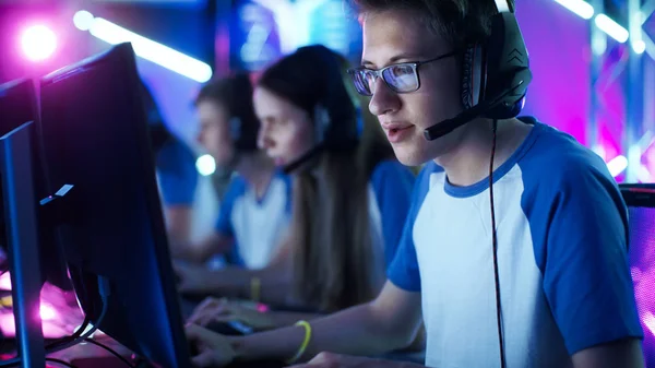 Команда подростков-геймеров играет в многопользовательской компьютерной видеоигре на турнире по киберспорту. Капитан дает команды в микрофон, пытаясь стратегически выиграть игру . — стоковое фото
