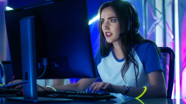 Vacker professionell Gamer Girl och hennes lag deltar i eSport Cyber Games Tournament. Hon har hörlurar och färgglada band på. — Stockfoto