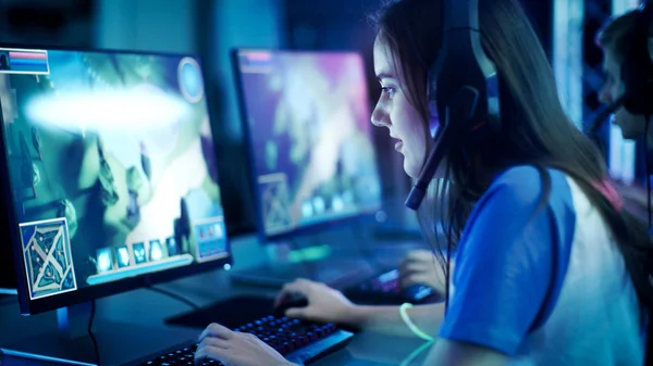 Jogadores profissionais jogam em MMORPG / jogo de estratégia em seu computador. Ela está participando de torneios online de jogos cibernéticos, jogos em casa ou no Internet Cafe. Ela usa fone de ouvido para jogos . — Fotografia de Stock