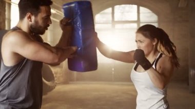 Atletik kadın trenler Her yumruk bir kum üzerinde çanta onun ortağı / eğitmen tutar. O profesyonel Fighter ve Hardcore spor salonu dışarıda eserlerinde..