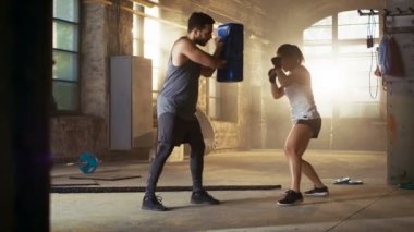 Atletik kadın sayısı kum torbası bu onun ortağı / eğitmen tutar. O profesyonel savaşçı ve bir spor salonu eğitimde.