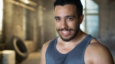 Kaslı adam silecekler ter alnına yoğun sonra Fitness vücut geliştirme eğitim çapraz. O tatlı gülümsüyor. Kolsuz gömlek ve inşaat dışarı bir spor salonunda giyiyor.