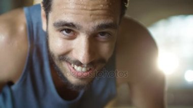 Kamera ve dinlenirken yoğun çalışmadan sonra yorgun Bend kaslı adam görünüyor. Bir spor salonunda o ve ter içinde kaplı. O bir nefes yakalamak için çalışır.