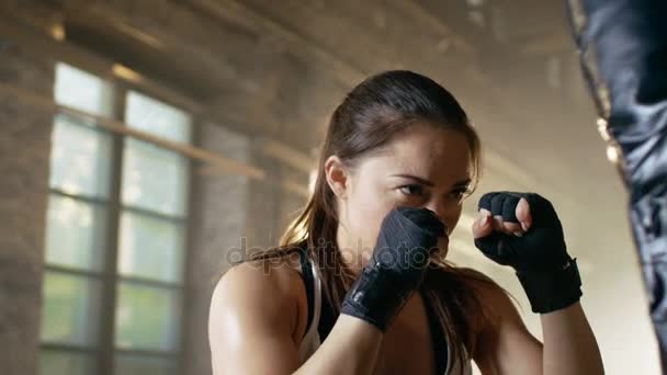 Mujer Entrenamiento de combate con saco de boxeo que sostiene su pareja. Ella es atlética y tiene un golpe poderoso . — Vídeos de Stock