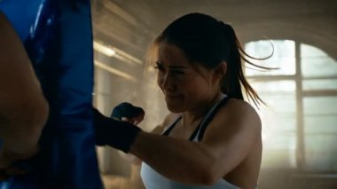 Atletik kadın sayısı kum torbası bu onun ortağı / eğitmen tutar. O profesyonel savaşçı ve bir spor salonu eğitimde.