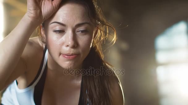 Die schöne athletische Frau wischt sich mit der Hand den Schweiß von der Stirn, blickt in die Kamera. Sie ist müde nach intensiver Crossfitness-Übung. — Stockvideo