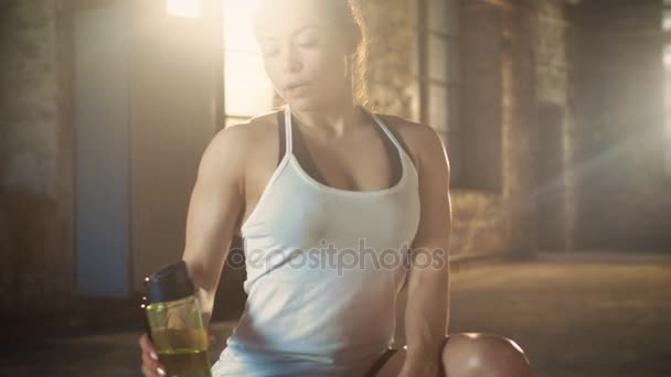 Сильная спортсменка пьет из бутылки воды после тренировки по бодибилдингу на кресте в любимом спортзале . — стоковое видео