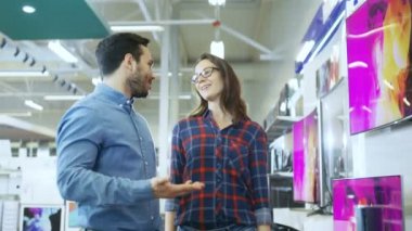 Genç çift yeni 4 için alışveriş k Tv elektronik mağazasında ayarlayın. En iyi Model üzerinde karar ama şüphelerim var etmeye çalışıyorlar.