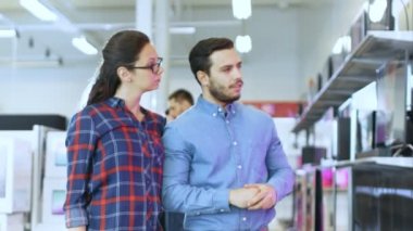 Genç bir çift yeni 4 k için televizyon elektronik mağazasında alışveriş. Onlar için mutlu aile evlerinin en iyi Model üzerinde verileceğine.