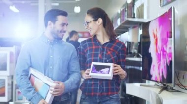 Mutlu çift elektronik mağazasında yürüyüş, onlar Tablet bilgisayar en yeni modeli ve yeni Smartphone için onun için satın aldığınız. Büyük, parlak ve tam en yeni elektronik alışveriş merkezidir.