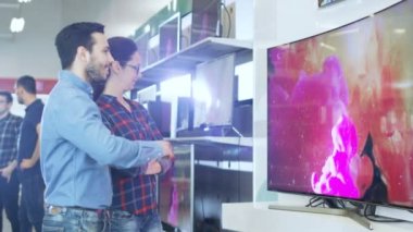 Genç çift yeni 4 k için alışveriş Uhd televizyon elektronik mağazasında ayarlayın. Onlar için mutlu aile evlerinin en iyi Model üzerinde verileceğine.