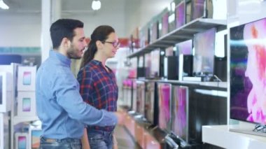 Genç çift yeni 4 k için alışveriş Uhd televizyon elektronik mağazasında ayarlayın. Onlar için mutlu aile evlerinin en iyi Model üzerinde verileceğine.