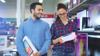 Mutlu çift elektronik mağazasında yürüyüş, onlar Tablet bilgisayar en son modeli ve yeni Smartphone için onun için satın aldığınız. Büyük, parlak ve tam en yeni elektronik alışveriş merkezidir.
