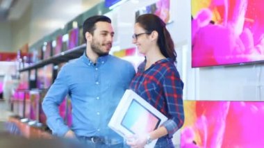 Genç çift elektronik mağazasında alışveriş yapar, onlar zaten kendileri için son Tablet bilgisayar seçti. Mağaza parlak, Modern ve son elektronik cihazlar var.