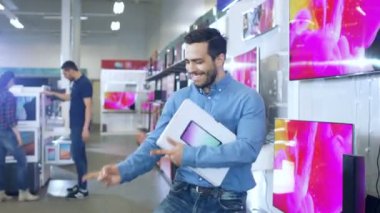 Elektronik mağazasından genç adam Tablet bilgisayar ve dansları kutusuyla mutlu son modeli satın aldı. Parlak ve Modern deposu vardır deposundaki tüm son cihazlar.