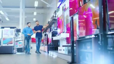Bir genç adam için elektronik mağaza profesyonel danışman gösterir son 4 k Uhd TV içinde ne Model ve teknik özellikleri hakkında konuşuyorlar iyisi genç adamın evi için. Mağaza parlak, Modern ve en son modelleri.