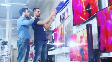 Bir genç adam için elektronik mağaza profesyonel danışman gösterir son 4 k Uhd TV içinde ne Model ve teknik özellikleri hakkında konuşuyorlar iyisi genç adamın evi için. Mağaza parlak, Modern ve en son modelleri.