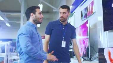 Bir genç adam için elektronik mağaza profesyonel danışman gösterir son 4 k Uhd TV içinde ne Model ve teknik özellikleri hakkında konuşuyorlar iyisi genç adamın evi için. Mağaza parlak, Modern ve en son modelleri.