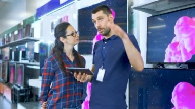 Elektronik mağazasında profesyonel danışman Tablet bilgisayar belirtme güzel genç kadın için uzman önerileri sağlar. Mağaza parlak, Modern ve en son aygıt olmadığı.