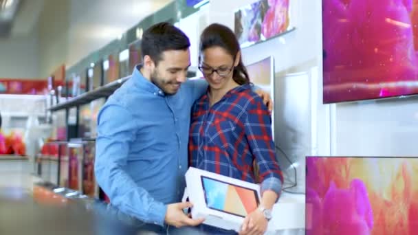 Young Couple In the Electronics Store Purchased Latest Model of a Tablet Computer, They're Very Much in Love and are Incredibly Happy. Store is Bright and Modern, Has all The Latest Devices. — Stock Video