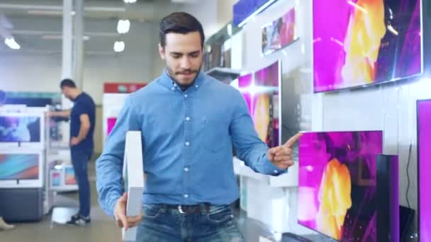 Mladý muž v obchodě s elektronikou zakoupit nejnovější Model tabletový počítač a tanců šťastně s pole. Světlé a moderní obchod má nejnovější zařízení v obchodě. — Stock video