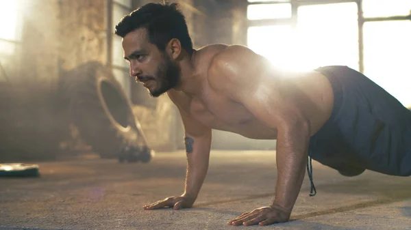 Muscular Shirtless Man Covered in Sweat Does Push-ups in a Deser