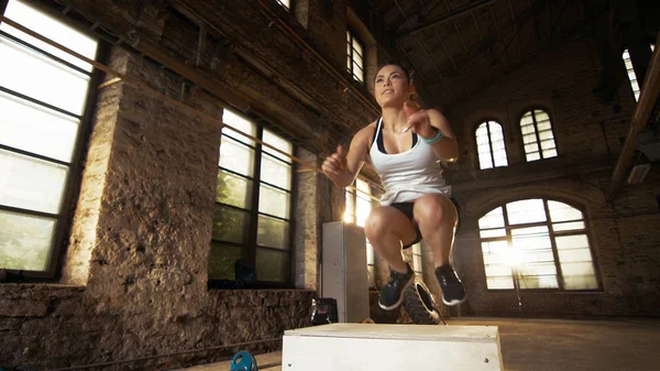 Forma atlética mulher caixa de saltos no ginásio fábrica abandonada. Eu — Fotografia de Stock