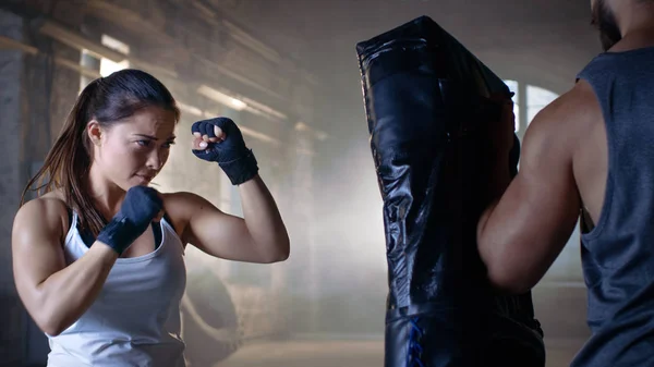 Athletic Woman Trains Her Punches on a Punching Bag that Her Par — Stock Photo, Image
