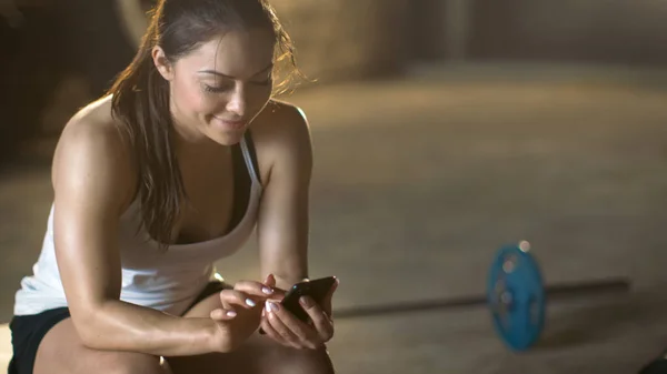 Bella bruna atletica utilizza Smartphone mentre si riposa sul — Foto Stock