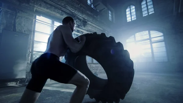 Sterke gespierde Man liften Tire als onderdeel van de nederlaag van zijn kruis Fitness — Stockfoto