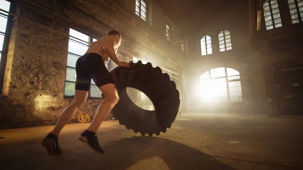 Hombre musculoso fuerte levanta neumático como parte de su cruz Fitness Prog —  Fotos de Stock