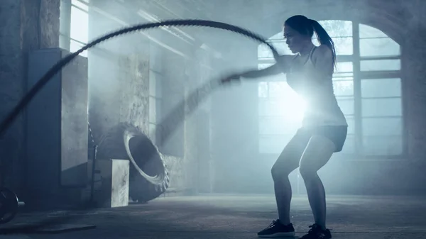 O femeie atletică puternică face exerciții cu corzi de luptă ca parte a ei — Fotografie, imagine de stoc
